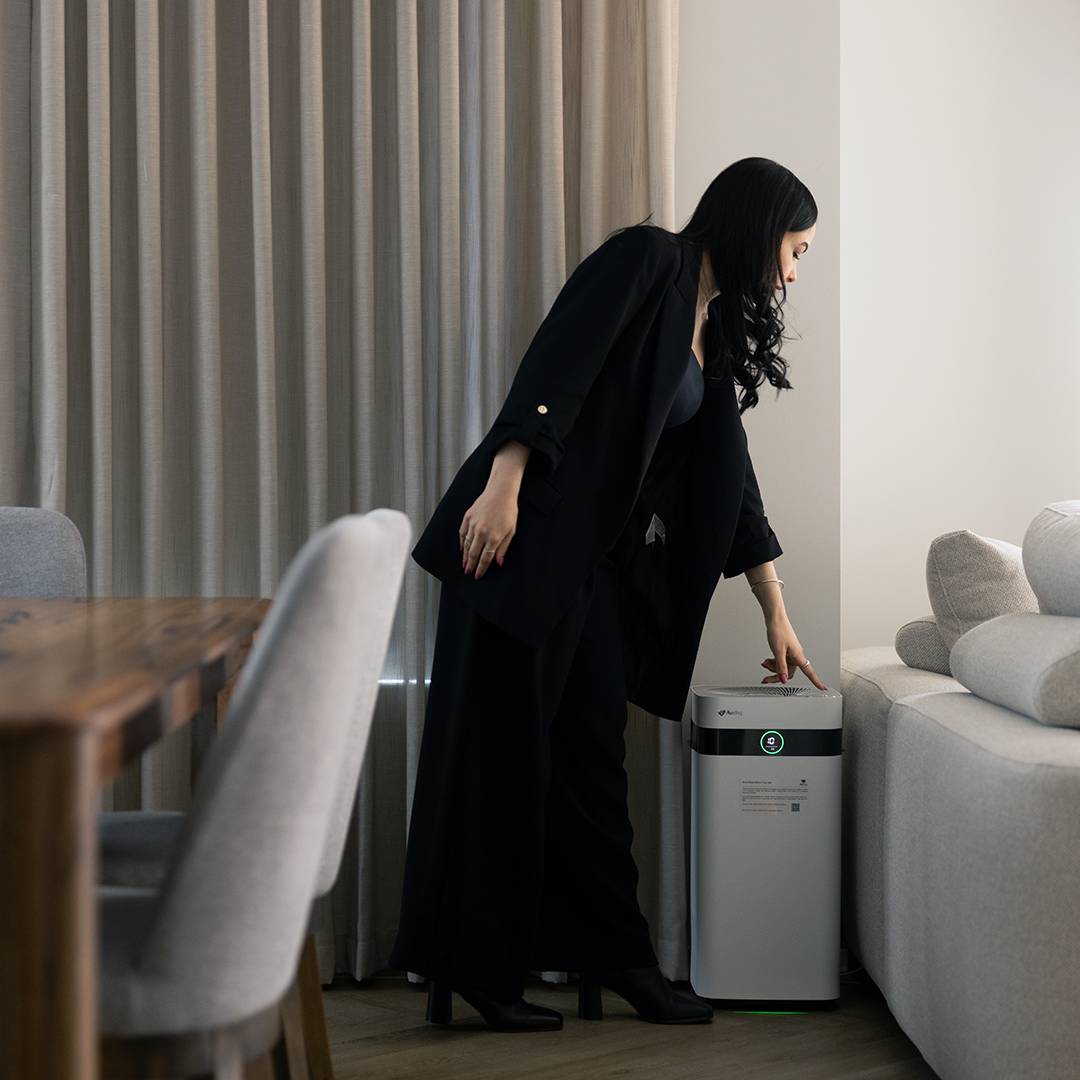 Woman in a black abaya interacting with an air purifier in a modern living room